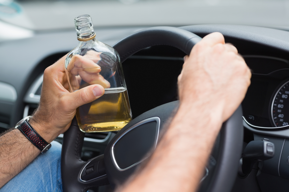 A Man Drinking Alcohol While Driving